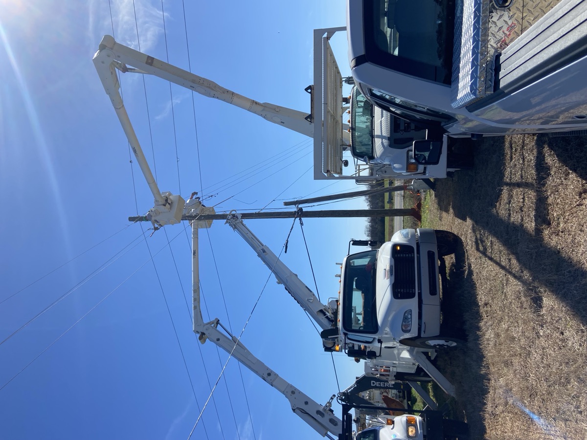 Three bucket trucks with booms raised around the pole on MLK Jr. Bypass